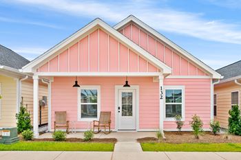 a pink house with two chairs in front of it